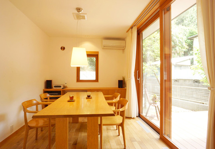 ダイニングルームの庭に面した大きな木製サッシ