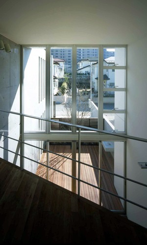 ２階から吹き抜けを見下ろし、ウッドデッキとシンボルツリーを眺める