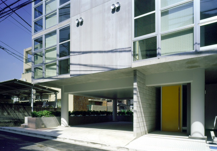 1階は、黄色い扉が特徴のエントランスと専用駐車場。地階は、オフィス。