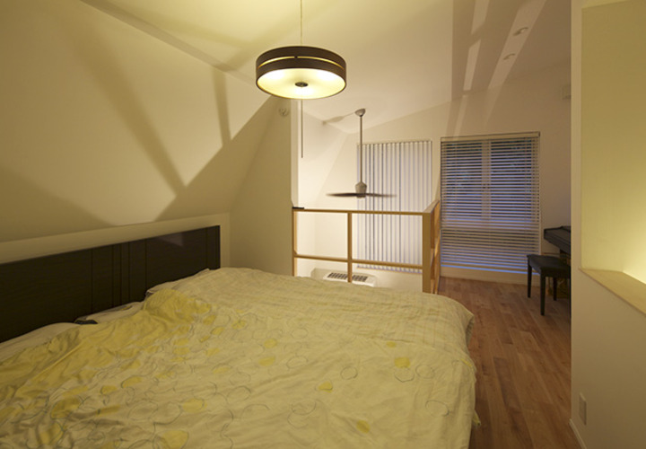 吹抜けから漏れる明かりが演出するベッドルーム