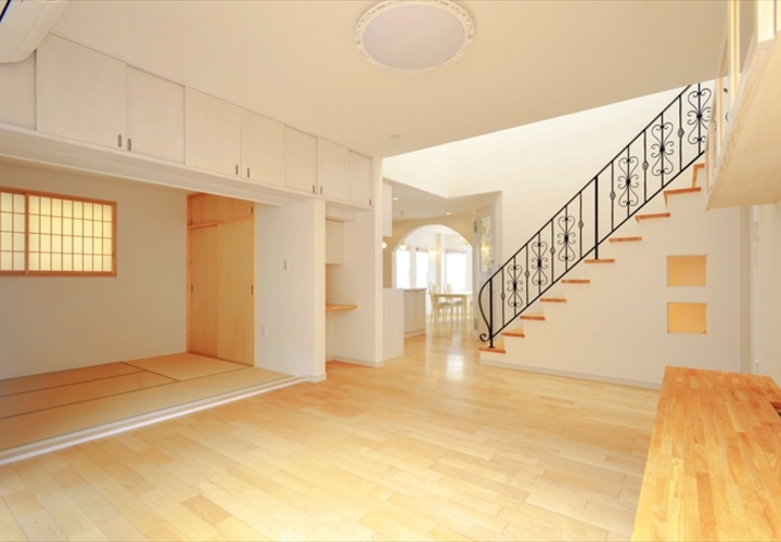 ロートアイアン手摺の付いた吹抜け階段から明るい光が差し込む広々リビング