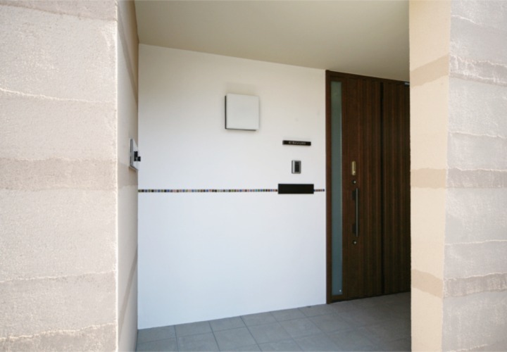 白い壁にタイルがデザインされたモダンな玄関