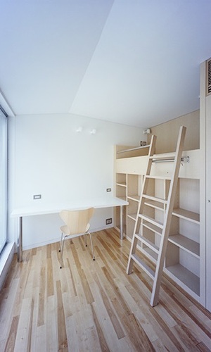 ベッドの裏は隣室の本棚となる収納家具