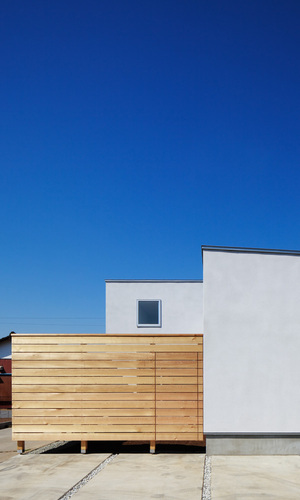 モルタル下地吹付塗装の継ぎ目のない外壁とレッドシダーの目隠し塀