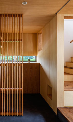 モルタル仕上の土間空間を縦格子でやわらかく仕切り奥はクロークスペース