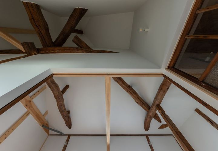 2階天井見上げ。寄棟の複雑な架構。壁・天井を白く塗った明るい空間。