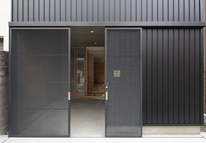 細身のエキスパンドメタル親子吊戸。普段は大きい戸を固定し小さい戸のみ開閉。自転車やバイクの出し入れ時は大小の戸を控壁へ収めて全開放。