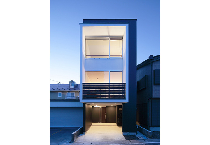 広い開口部から灯りの漏れる夕景外観