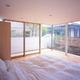 全面窓で柔らかな朝日が注ぐ寝室