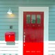 ミントグリーンの外壁にビビットな赤いドアが映えるカラフルな玄関