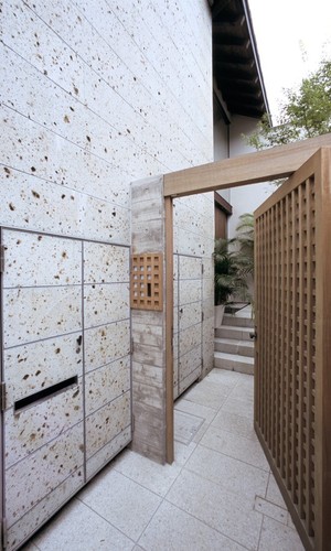 大谷石の外壁と木格子の門扉がアジアンリゾートな雰囲気のアプローチ