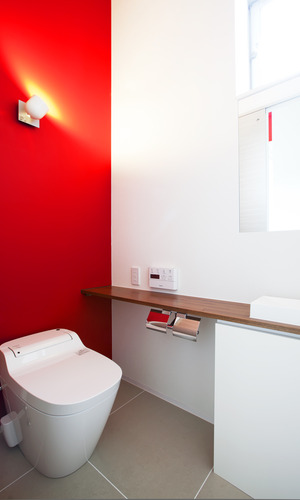 単調になりがちなトイレ空間の、アクセントになる色鮮やかな赤色の壁