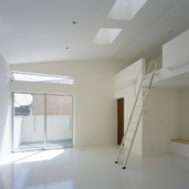 斜め天井より差し込む光が白い床に反射する、のびやかなリビング