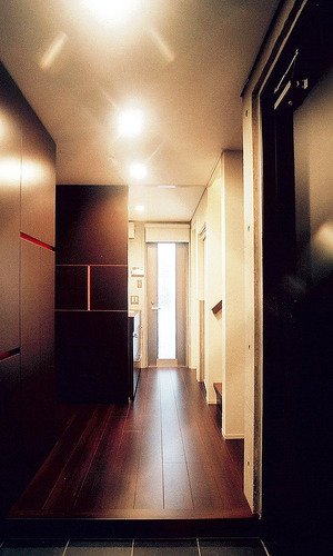 焦げ茶のフローリングと収納棚色を合わせた、影の美しさを感じる廊下