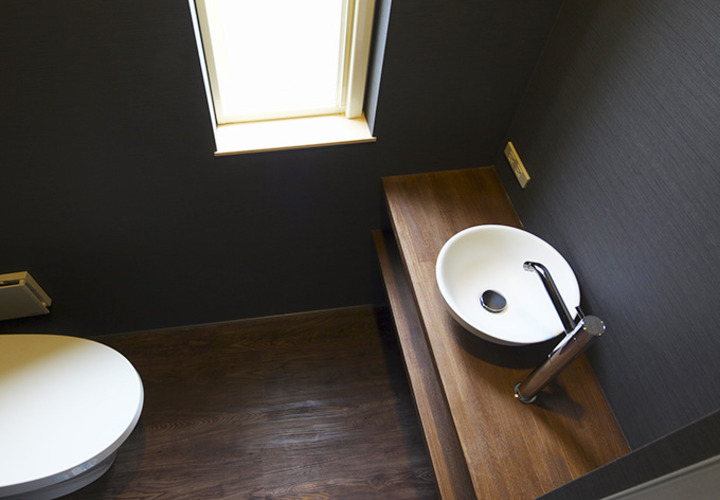 黒い壁とウッド調が落ち着きある雰囲気のトイレ