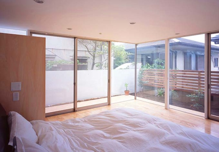 全面窓で柔らかな朝日が注ぐ寝室