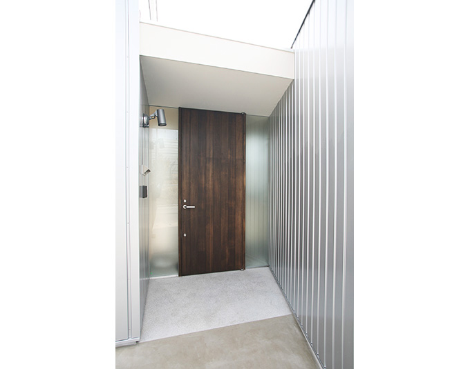 重厚な木の玄関ドアと金属製の外壁のコラボ