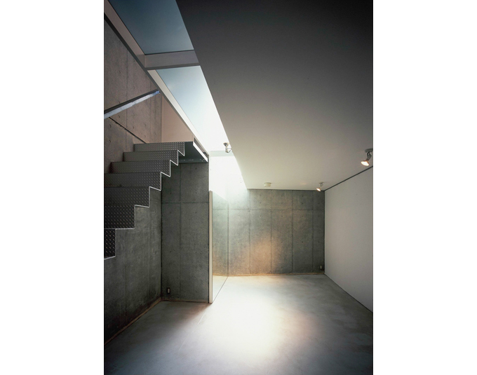 トップライトの光が降り注ぐコンクリート壁のリビング