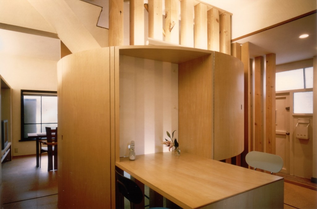 円形の印象的な収納棚と共に造り付けのダイニングテーブル