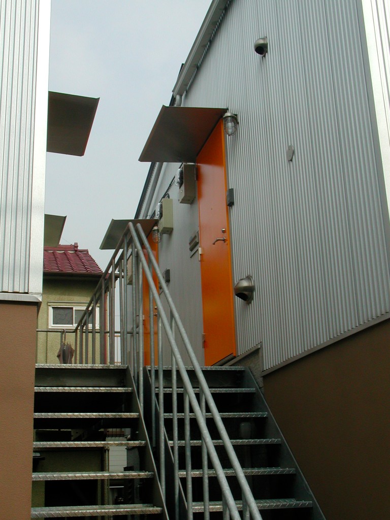 ガルバリウムの外壁に鮮やかなオレンジ色の玄関ドア