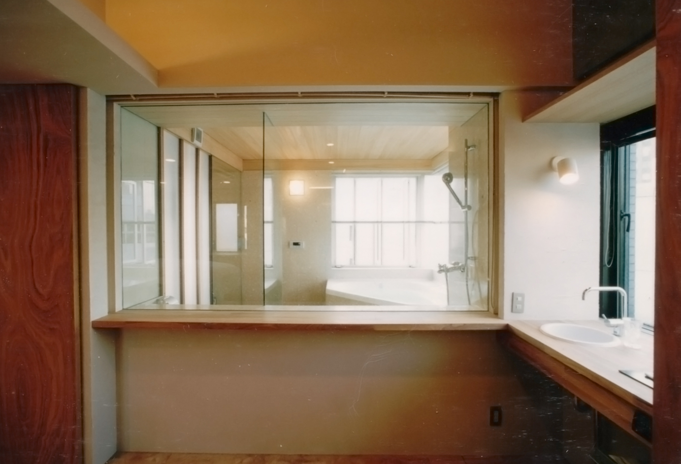 バスルームのガラス張りから明るい光が差し込む洗面スペース