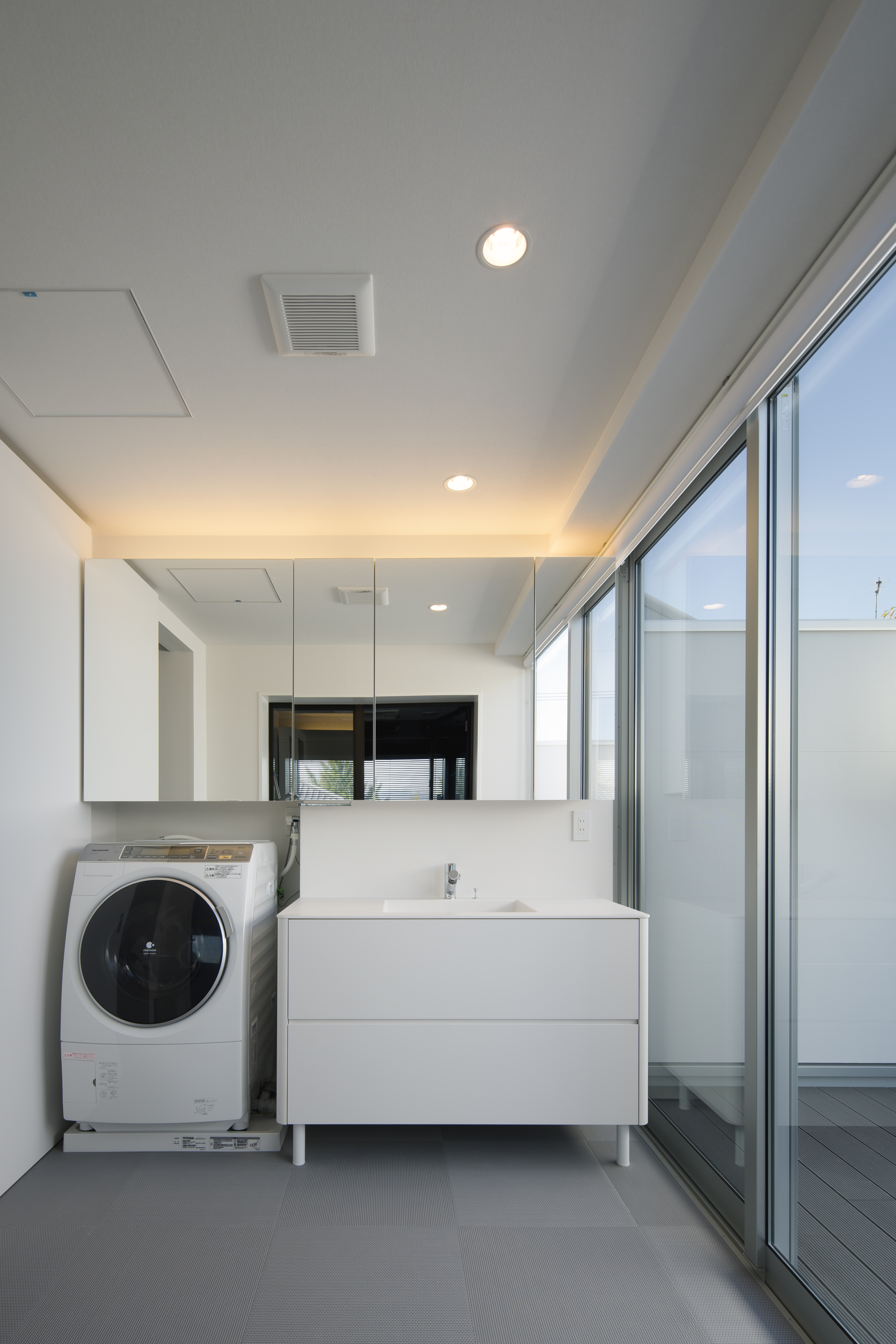窓一面から入る光が、衛生的かつ清潔感ある白でまとめられた洗面所