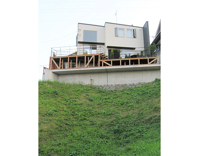 丘の上に佇む家を見上げる