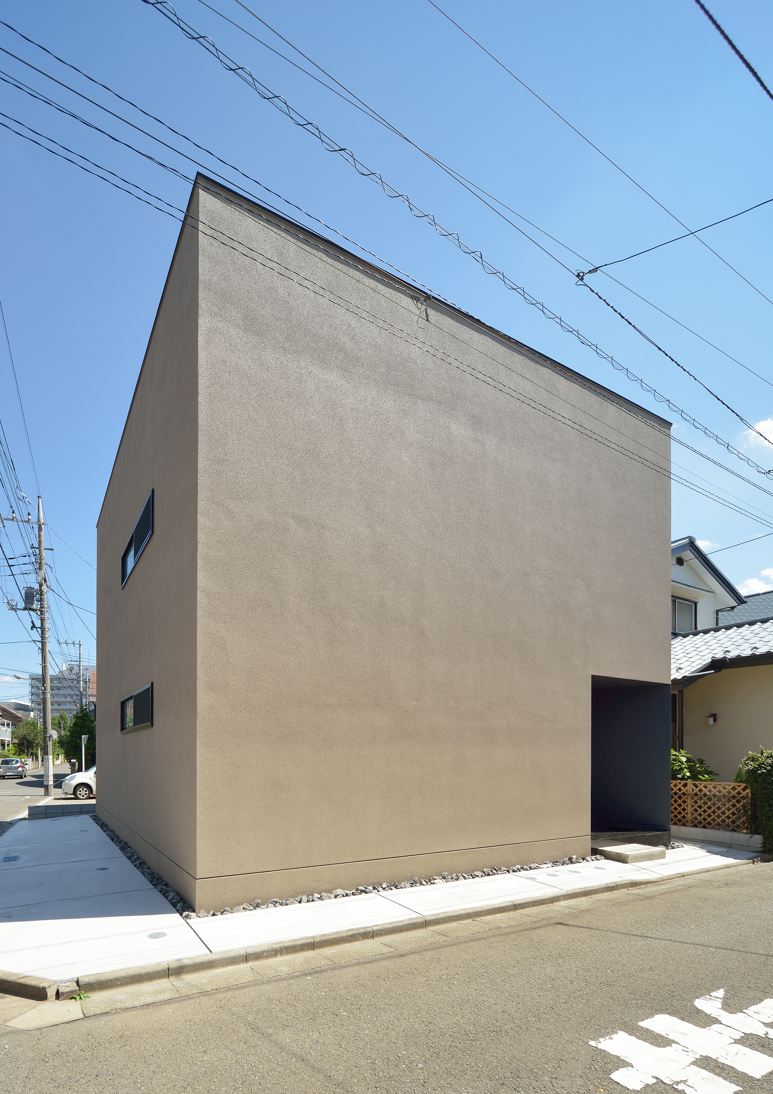 洞窟のようなテクスチャーの外壁に、スクエア型のシンプルな外観