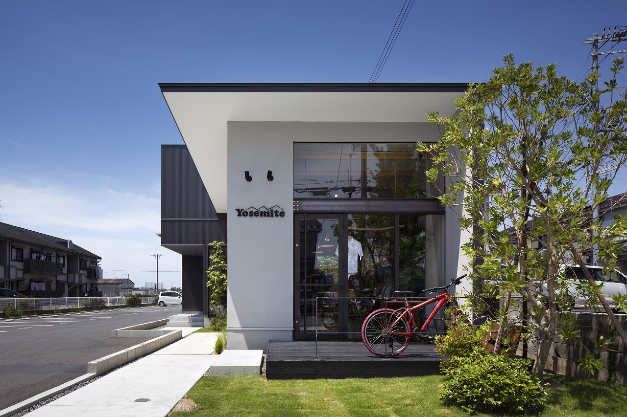 白い塗り壁に芝生と木々の緑が眩しいアトリエ