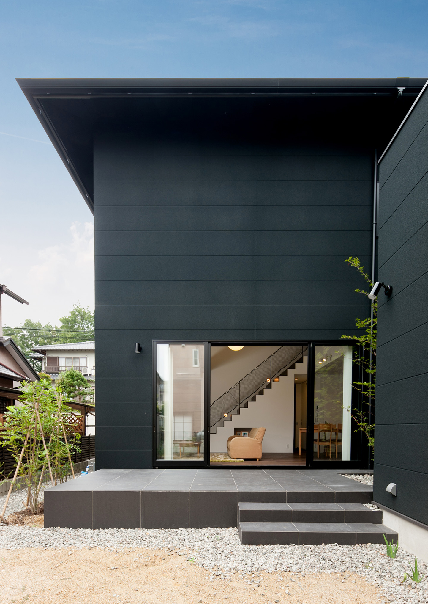 黒い面積が多い外壁から伸びるように広がる中庭