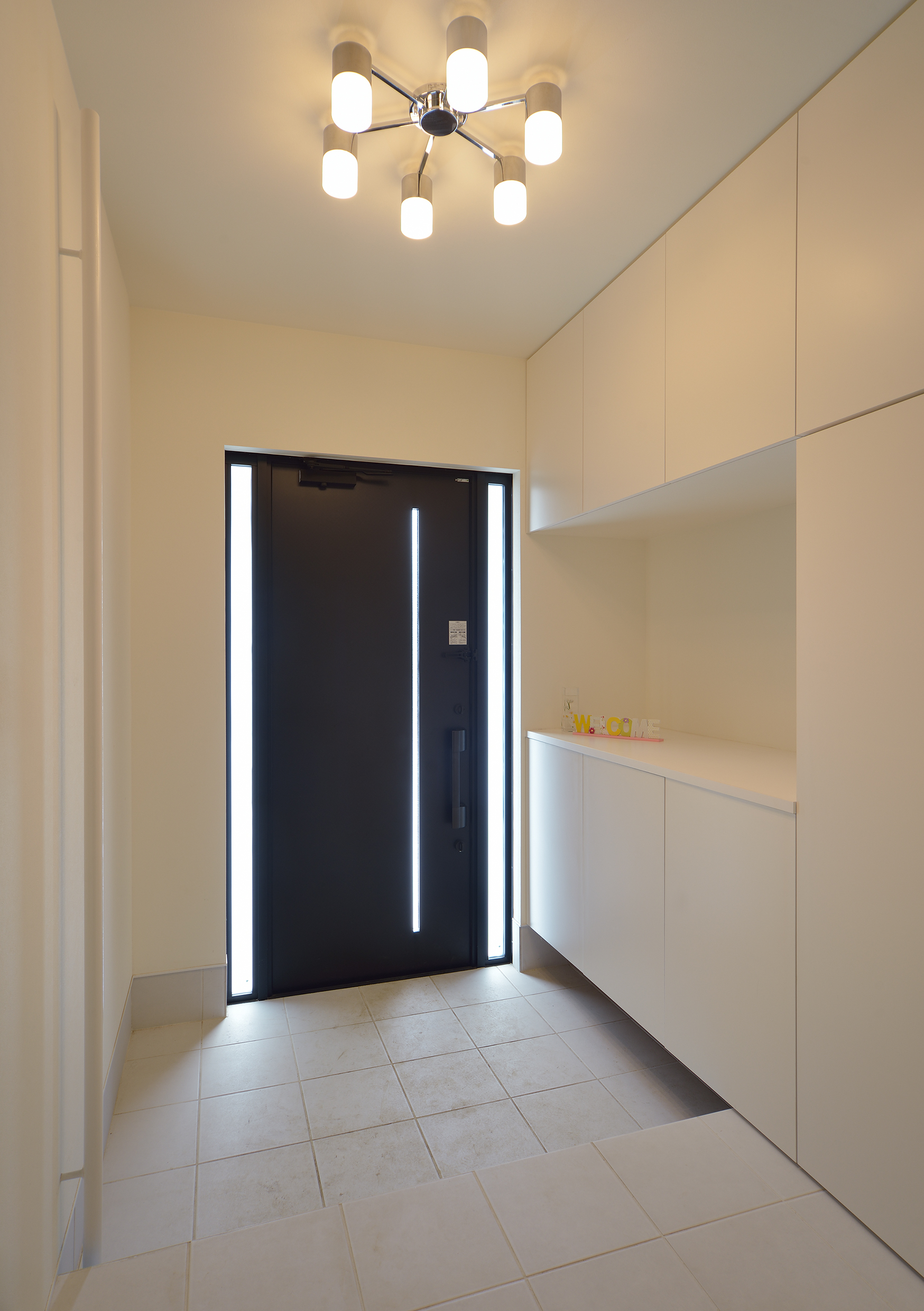 玄関ドア横スリットから入る光が、白をメインに広々とした空間に映える