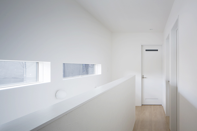 白い空間に日差しを取り込む階段横の窓