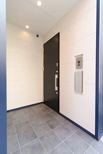 外壁とコントラストのある白壁に囲まれた玄関