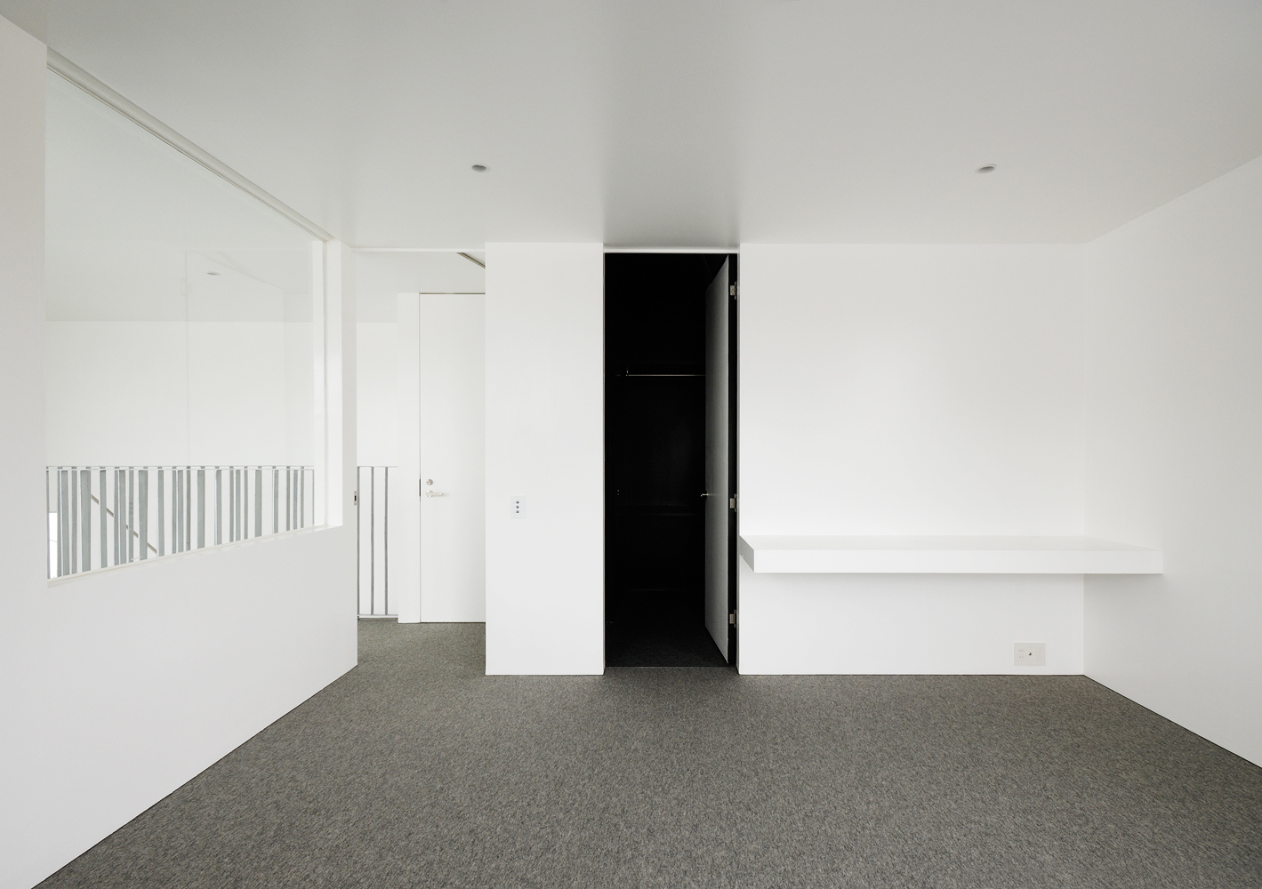 白とグレーで囲まれた部屋内に設けた、引き締まった黒色を用いたウォーキングクローゼット