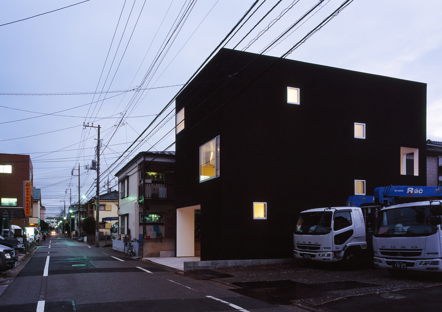 真っ白な額縁のような窓から、優しいオレンジの光に変わる夕方の外観