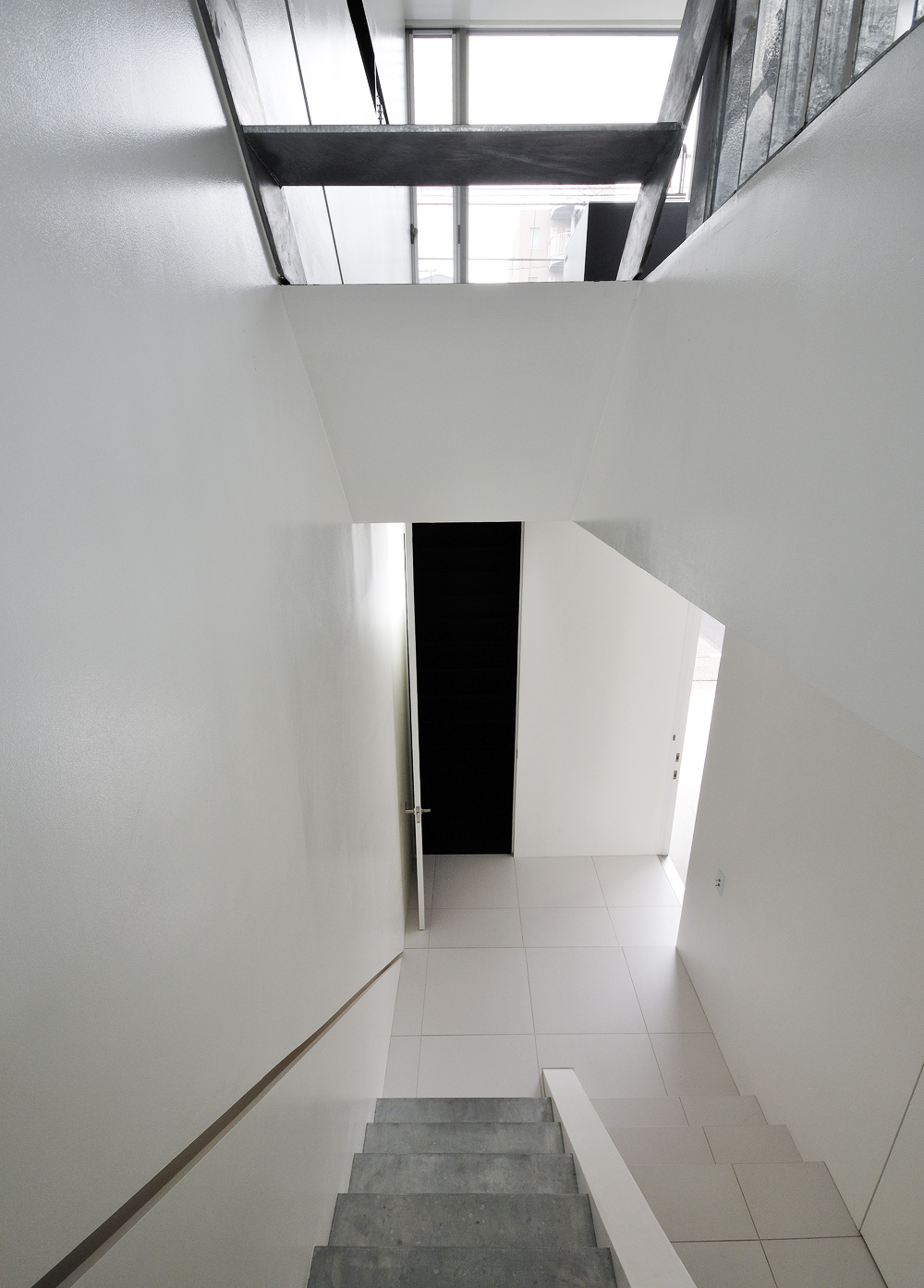 美しい白の床壁と、素材そのものが活かされた階段が新鮮な玄関ホール