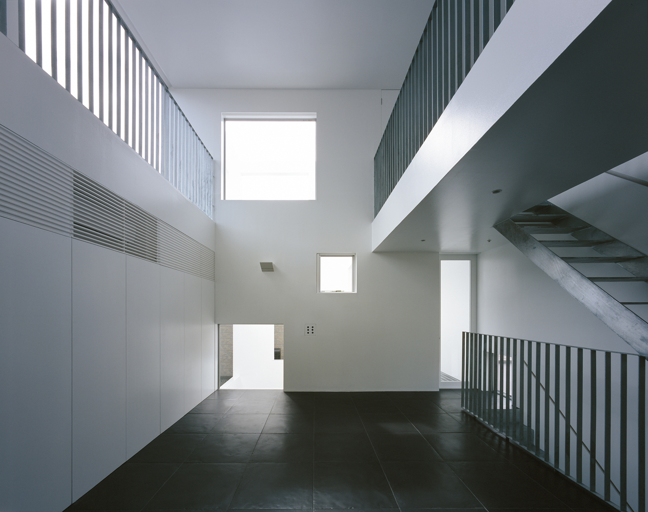 大きめの黒タイルと金属を用いた手すりと階段が、まるで美術館のようなリビングダイニング