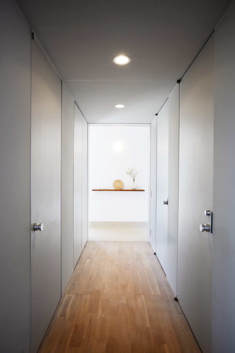淡いグレーで統一された、全体的に光を絞ったトンネルのような廊下