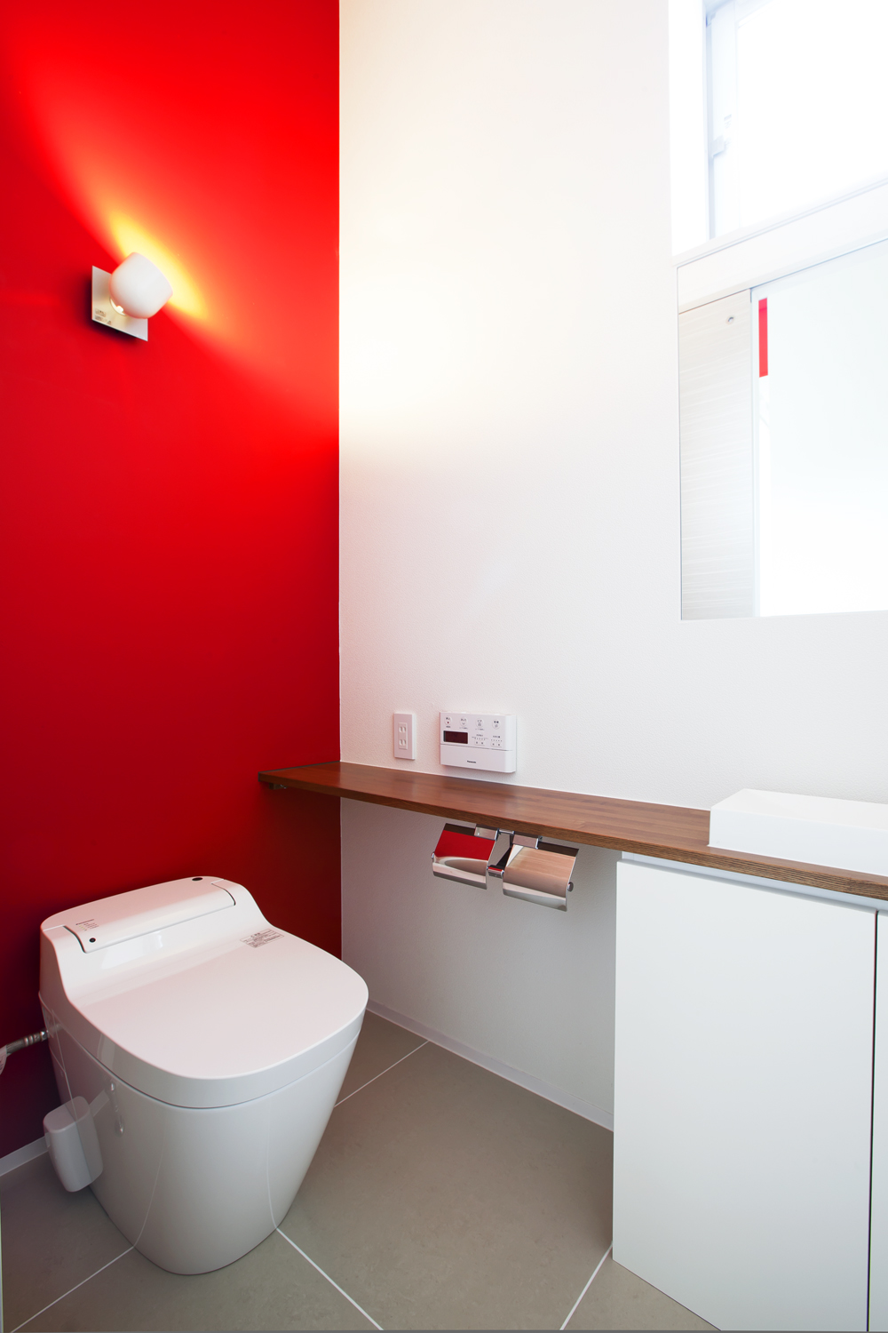 単調になりがちなトイレ空間の、アクセントになる色鮮やかな赤色の壁
