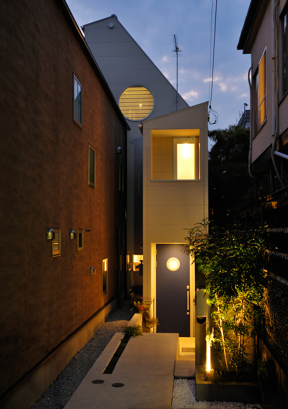 旗竿上の敷地に建つ、大きな丸窓と青い玄関の小さい丸窓が印象的な外観