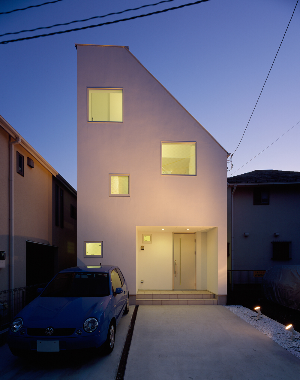 閑静な住宅街に、潔い白さ放つ外壁とランダムな配置の窓から穏やかな光が溢れる外観夜景