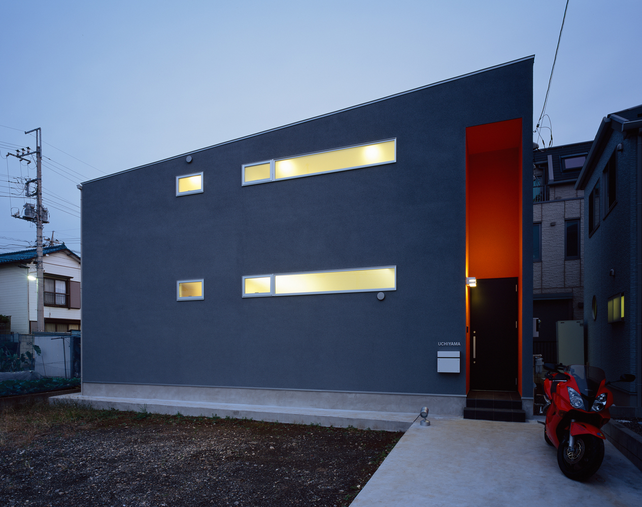 グレーの外壁にオレンジ色のエントランスが印象的な外観 Fevecasa フェブカーサ