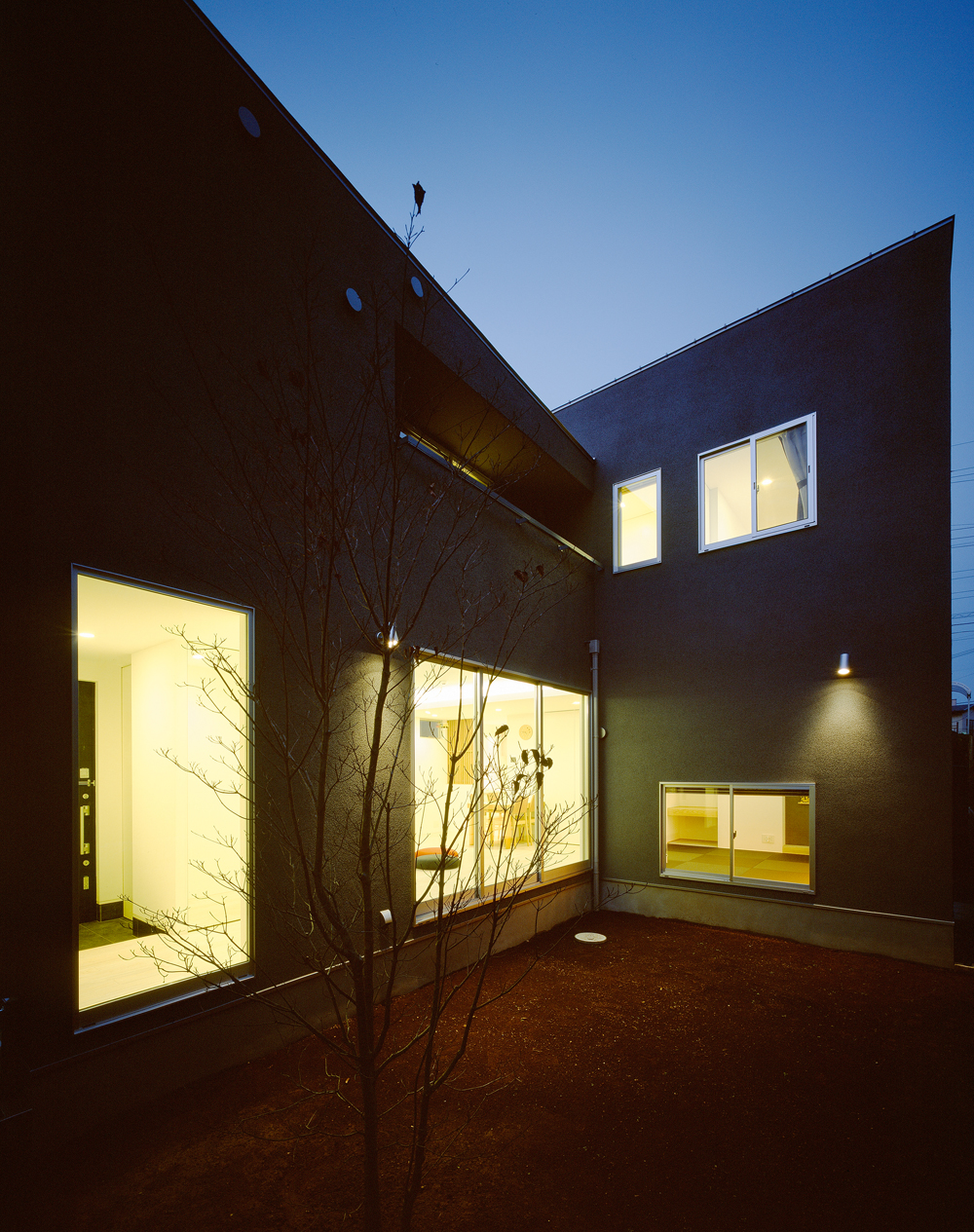 グレーの外壁が闇を作り、窓からこぼれ出る光が美しい中庭