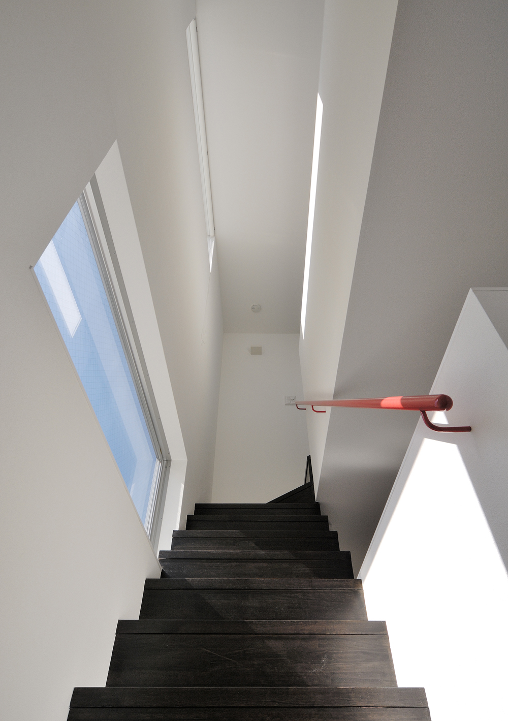 赤い手摺が、各階の家族の空間をつなげていく階段