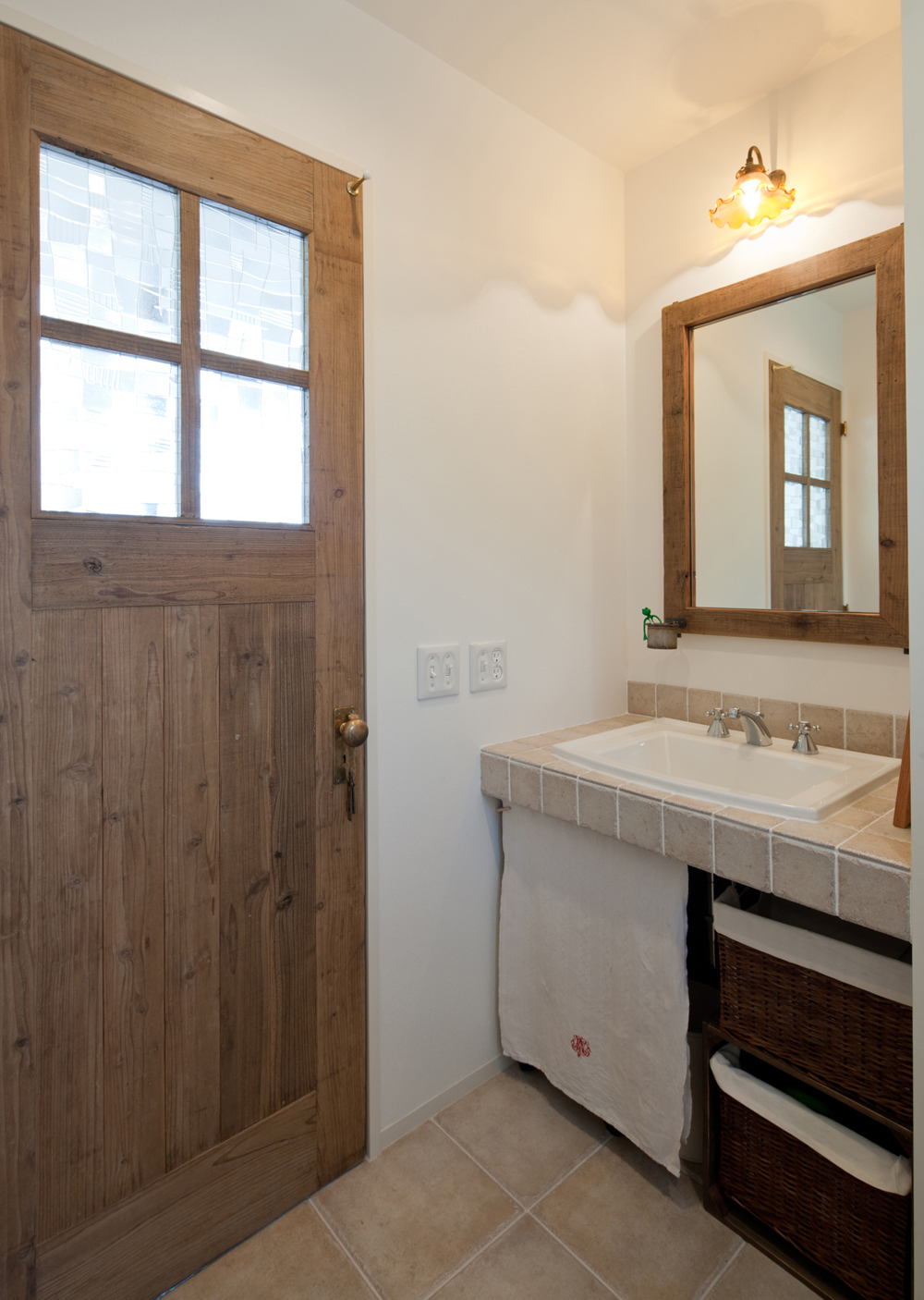 輸入洗面器とタイル、建具と鏡の枠は古木を再利用して作られた一品物と、こだわりぬいた洗面所