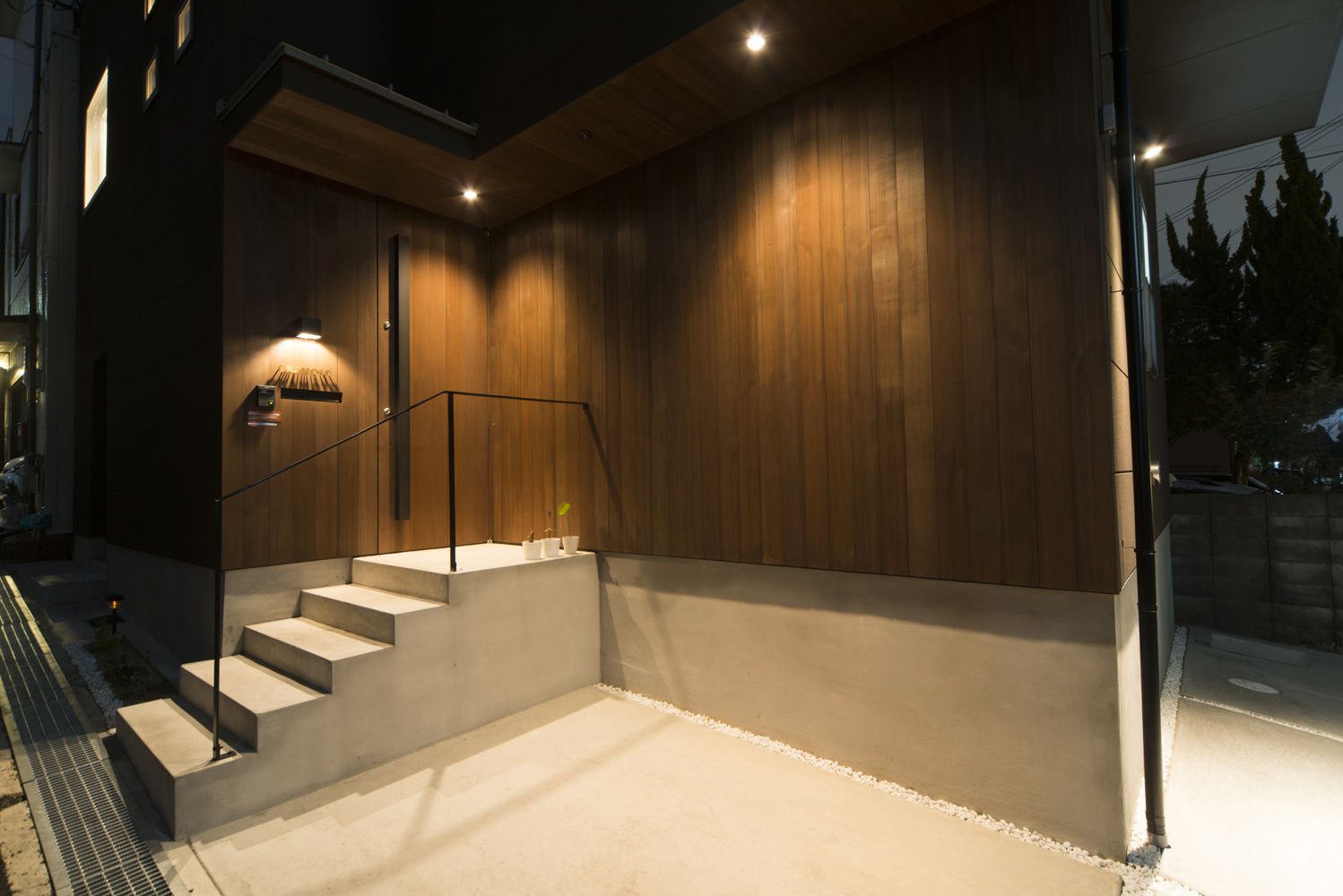 深みのある色合いの木外壁とダウンライトが、バーのような雰囲気に仕上げた玄関