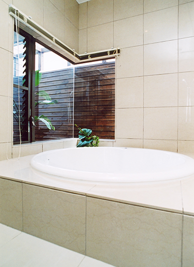 リゾート気分の丸い浴槽に自然光の注ぐ浴室