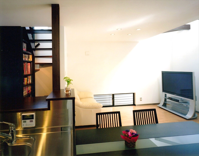 ダイニングキッチンからリビングと開放的な階段を見る