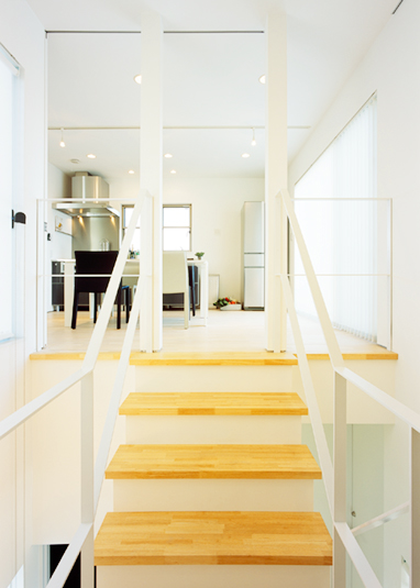 木のオープン階段からキッチンを眺める