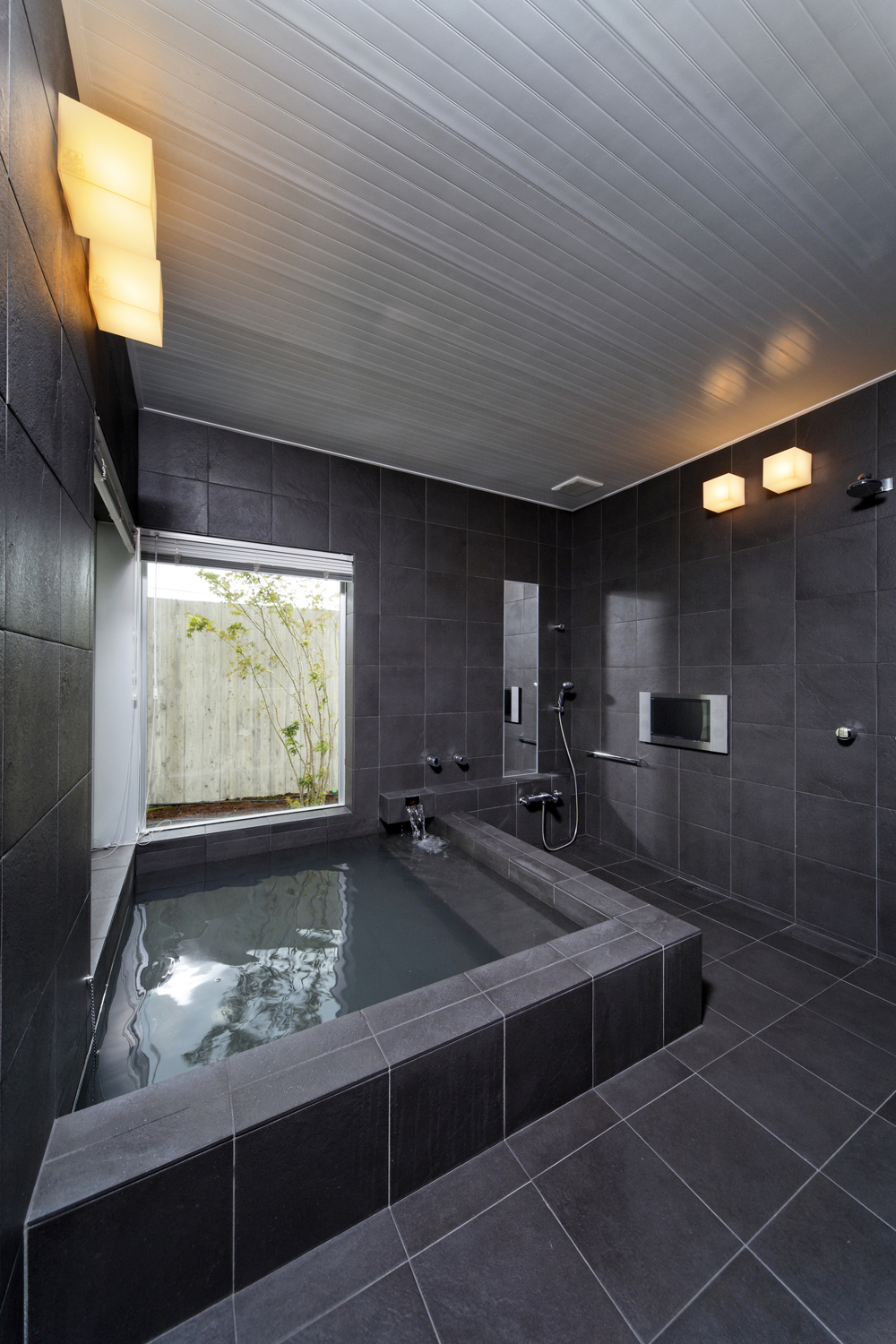 黒のタイル張りが重厚感のある 温泉が引かれた浴室 Fevecasa フェブカーサ